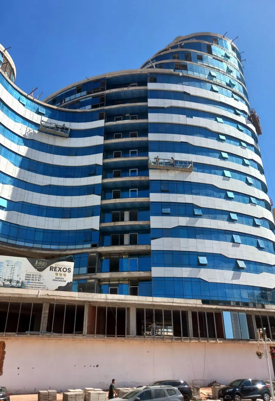 Résidence Rexos en cours de construction, façade en verre bleu et bandes argentées